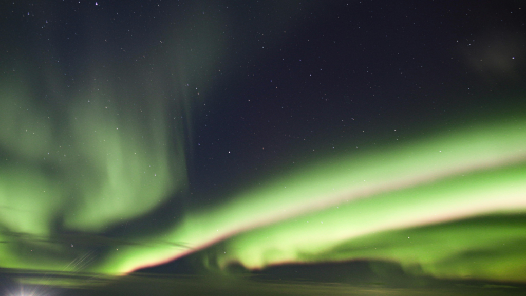 Intense Northern Lights display reflecting on frozen Great Slave Lake near Yellowknife, Northwest Territories, 2026.