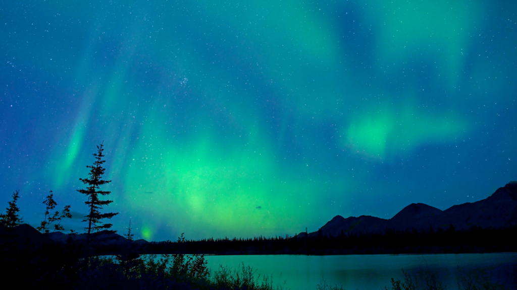 Vibrant green Aurora Borealis dancing over traditional teepees at Aurora Village in Yellowknife during 2026 winter night.